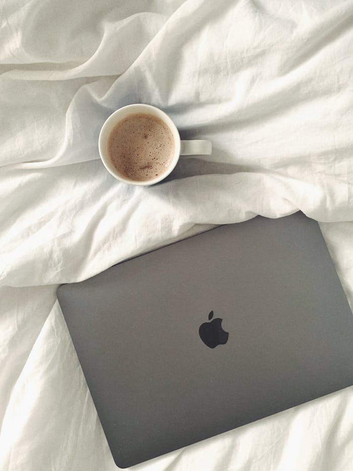 Laptop Beside a Cap of Coffee on White Textile